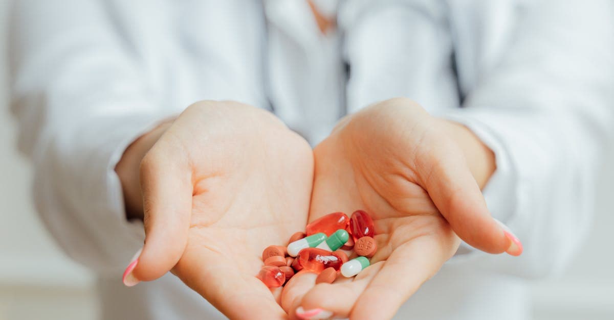 Two hands holding pills and vitamins.